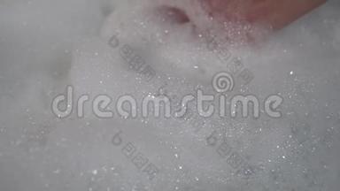 一个男人从浴缸里抓起一堆新鲜的卫生泡沫